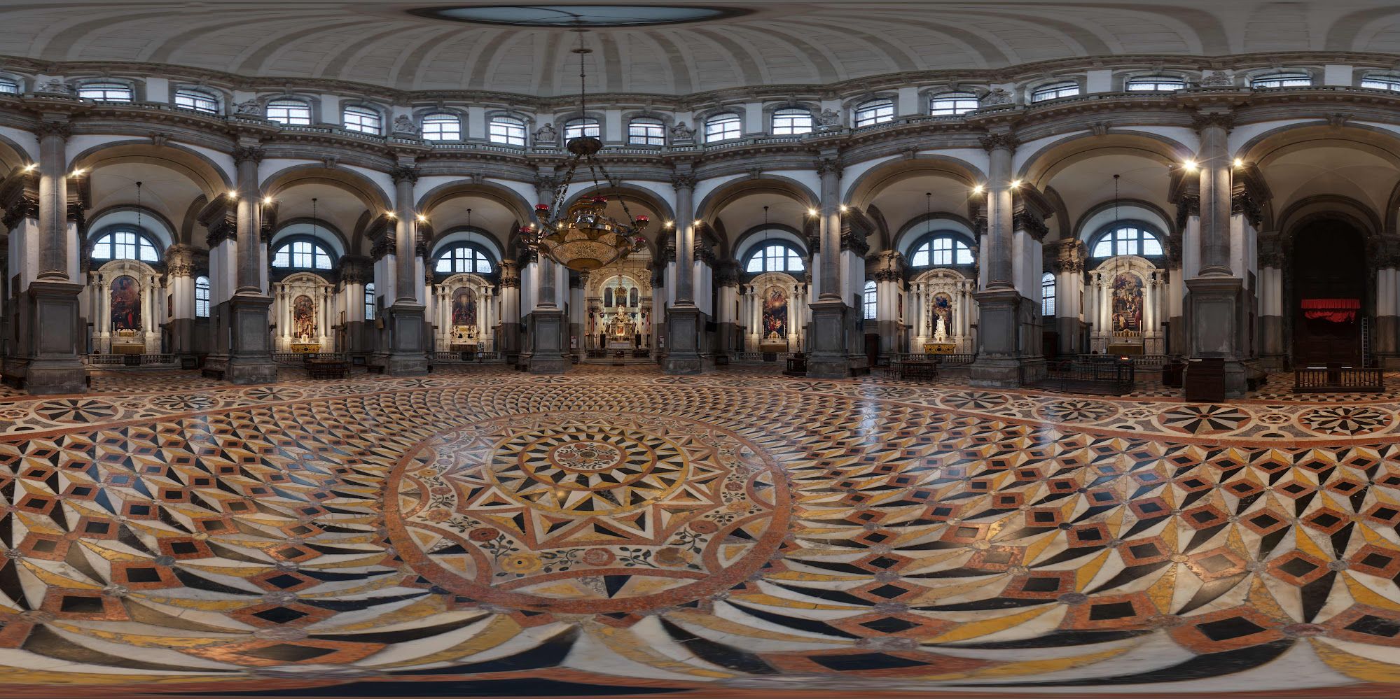 Basilica interior with decorative floor patterns and person standing with balloon on opposite side with microphone on the other side in between pillars and archways